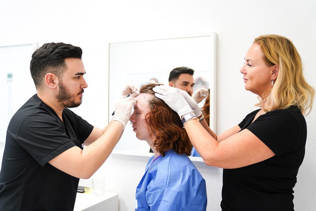 Hair technichian draws hairline on patients forehead maggie holds unshaven long hair back
